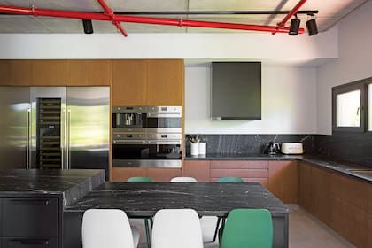 Amoblamiento con frentes de reconstituido de petiribí, volumen de chapa negra (todo de Estudio Karina Kreth) sobre el extractor ‘Recta Soft’ (Spar Franke). Mesadas y alzadas de mármol ‘Ebony Black’ con terminación leather.