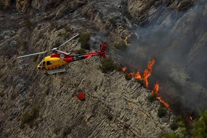 An AS-350 "Ecureuil" fire-fighting helicopter takes part in fire containment operations in Artesa de Segre, in Catalonia on June 16, 2022. - Emergency services battled several wildfires as Spain remained in the grip of an exceptional heatwave that has seen temperatures reach 43 degrees Celsius (109 degrees Farenheit). The most alarming blaze, near Baldomar in Catalonia, has already destroyed 500 hectares of forest but could spread to over 20,000, the government in the northwestern region said. (Photo by Pau BARRENA / AFP)