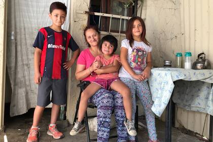 Analía con tres de sus nueve hijos, en la puerta de su casa en Burzaco