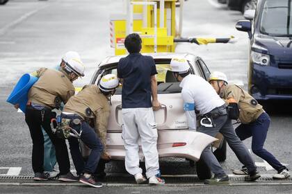 Varias personas mueven una auto que voló a causa de los fuertes vientos y quedó en medio de una carretera