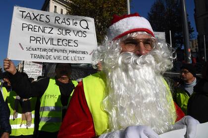 "Suficientes impuestos, metete con tus propios privilegios", dice el cartel de un Papá Noel con chaleco amarillo