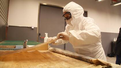 Andrea Rocca, de área de patrimonio de Sbase, despliega uno de los mapas que estaba congelados junto a otros 50.000; están confeccionados en tela o papel y los más antiguos pueden ser de fin de 1800