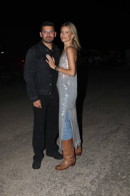 Angie Landaburu junto a su novio, el empresario Augusto Marini. La influencer de moda eligió un vestido largo sin mangas de lentejuelas que combinó con un jean y botas