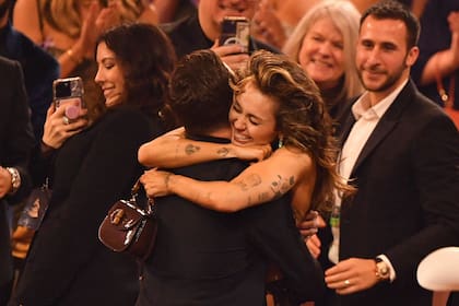 Anoche Miley Cyrus se sacó el gusto al obtener los dos primeros grammy de su carrera por su hit "Flowers"; uno de ellos fue el de mejor grabación del año; en la foto, tras el anuncio del galardón, Cyrus abraza a Michael Pollack, uno de los coautores y productores de la canción