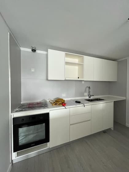 ANTES. Una cocina con poco para ofrecer en lo estético y menos espacio de guardado. Ahora sumó lugar para ocultar el lavarropas, el microondas y se agregó una estación de café dentro de un nuevo volumen.