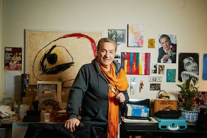 Antonio Grimau en su casa, pincel en mano, con algunos de sus cuadros detrás.