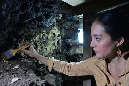 La antropóloga mexicana Lorena Velázquez Vallin limpiando un descubrimiento reciente del extremo oriental y la fachada externa del Huei Tzompantli