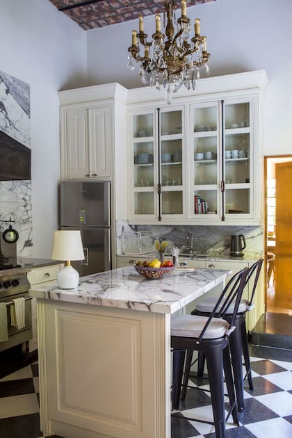 Apenas dos elementos bastaron para renovar la cocina: sumar una isla y ajustar la altura de la antigua araña de caireles que pende justo sobre ella.