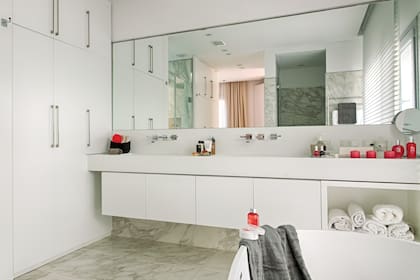 Aquí, las bachas, mesadas y zócalos son una sola pieza de Corian. El mueble es de termoformado satinado blanco.
