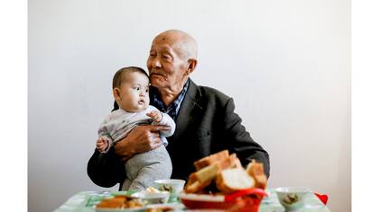 El ex pescador Sagnai Zhurimbetov, de 84 años, sostiene a su bisnieto de 10 meses Ykhlas en su casa en la antigua ciudad marítima de Aral