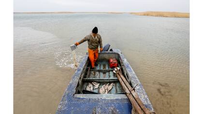 Un pescador saca agua de su bote en la costa del mar de Aral, en las afueras del pueblo de Karateren