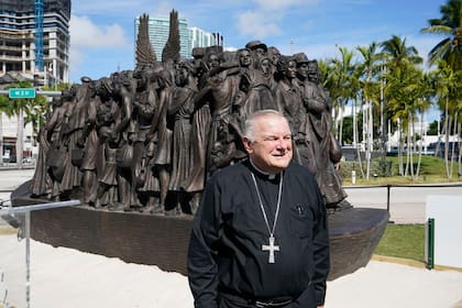 ARCHIVO - El arzobispo de Miami, Thomas Wenski, posa frente a una escultura itinerante de bronce titulada "Ángeles desprevenidos", antes de bendecirla el 10 de febrero de 2021 en el centro de Miami