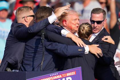 ARCHIVO - El candidato presidencial republicano, el expresidente Donald Trump, es rodeado por agentes del Servicio Secreto de Estados Unidos quienes lo ayudan a bajar del escenario en un mitin de campaña en Butler, Pensilvania, el 13 de julio de 2024. (Foto AP/Gene J. Puskar, Archivo)
