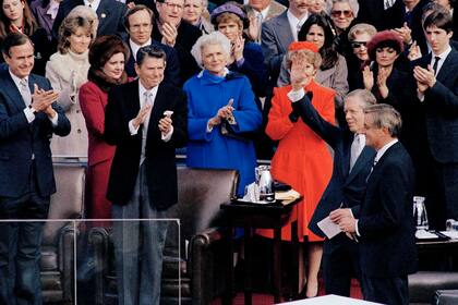 ARCHIVO – El presidente electo Ronald Reagan aplaude mientras el presidente saliente Jimmy Carter saluda a la multitud en la ceremonia de investidura de Reagan, en Washington, el 20 de enero de 1981. (AP Foto, Archivo)