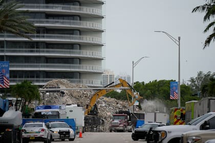 ARCHIVO - En esta fotografía de archivo del 12 de julio de 2021, una excavadora retira escombros de la sección demolida del complejo de condominios Champlain Towers South, mientras prosiguen las labores de recuperación de restos humanos en el lugar, en Surfside, Florida. (AP Foto/Rebecca Blackwell, Archivo)