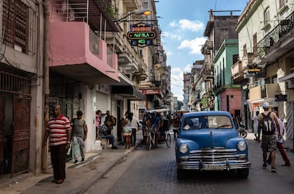 Archivo.- La gente camina bajo un cartel que anuncia una tienda de comestibles privada, a la izquierda, en La Habana, Cuba, el 11 de noviembre de 2023