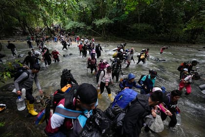 ARCHIVO - Migrantes, en su mayoría venezolanos, cruzan un río en la selva del Darién el 15 de octubre de 2022, en un recorrido de Colombia a Panamá, con la esperanza de seguir luego su viaje hacia Estados Unidos. La Agencia de la ONU para los Refugiados (ACNUR) y la Organización Internacional para las Migraciones (OIM) indicaron en un comunicado el jueves 13 de abril de 2023 que más 100.000 migrantes cruzaron esa ruta en los primeros meses del año y que, de seguir la tendencia, la cifra a final del año podría superar los 400.000. (AP Foto/Fernando Vergara, Archivo)