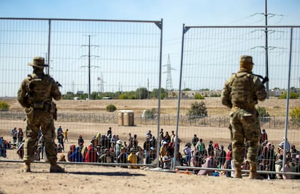 ARCHIVO - Migrantes esperan junto a una valla fronteriza bajo la vigilancia de la Guardia Nacional de Texas para ingresar a El Paso, Texas, el 10 de mayo de 2023 (AP Foto/Andres Leighton)