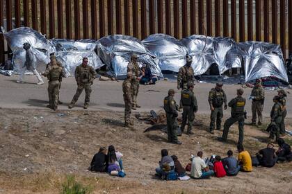 Archivo.- Migrantes esperan ser procesados ​​por las autoridades estadounidenses en el lado estadounidense de la frontera entre Estados Unidos y México, visto desde Tijuana, estado de Baja California, México, el 11 de mayo de 2023