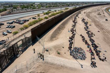 Archivo.- Migrantes forman filas frente a la valla en la frontera de Estados Unidos con México a la espera de ser transportados a una instalación de la Patrulla Fronteriza, el 10 de mayo de 2023, en El Paso, Texas (AP Foto/Andrés Leighton, Archivo)