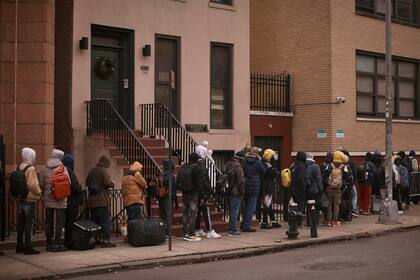 ARCHIVO - Migrantes hacen cola en el frío mientras buscan un refugio fuera de un centro de asistencia a migrantes en la escuela primaria St. Brigid, el 5 de diciembre de 2023, en Nueva York. (AP Foto/Andres Kudacki, Archivo)