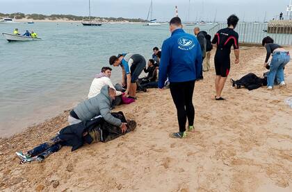 ARCHIVO - Migrantes son auxiliados por pobladores en una playa cercana a la ciudad de Cádiz, España, el jueves 30 de noviembre de 2023. (AP Foto/Jorge Gonzalez Casares, archivo)