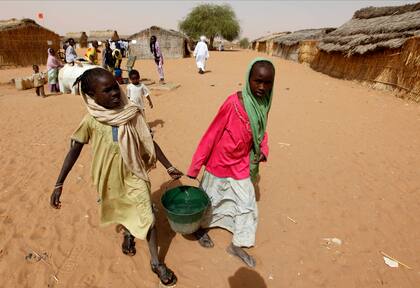 ARCHIVO - Niñas refugiadas de Sudán cargan agua cerca de un centro de votación en el campo de refugiados de Zamzam, a las afueras de El Fasher, Darfur, Sudán (AP Foto/Nasser Nasser, Archivo)