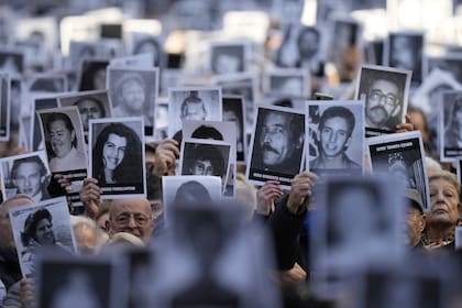 ARCHIVO - Personas sostienen fotografías de víctimas mientras suenan las sirenas durante una ceremonia que marca el 30 aniversario del bombardeo del centro judío AMIA que mató a 85 personas en Buenos Aires, Argentina, el 18 de julio de 2024. (AP Foto/Natacha Pisarenko, Archivo)