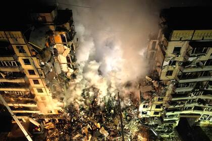 Archivo.- Trabajadores de emergencias retiran escombros después de un ataque ruso contra un edificio de apartamentos que atrapó a mucha gente bajo los escombros en la ciudad suroriental de Dnipro, Ucrania, el sábado 14 de enero de 2023 (AP Foto/Evgeniy Maloletka)