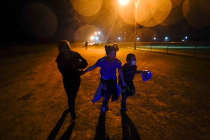 Archivo- Tres niños migrantes corren bajo la lluvia luego de entregarse a las autoridades tras cruzar la frontera entre Estados Unidos y México, el 11 de mayo de 2021, en Roma, Texas (AP Foto/Gregory Bull, Archivo)