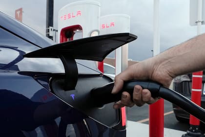 ARCHIVO - Un automovilista carga su vehículo eléctrico en una estación de Tesla en Detroit. La marca fundada por Elon Musk lidera las ventas de eléctricos en el mundo