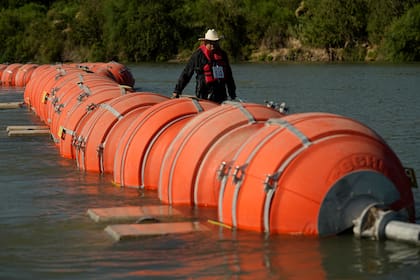 ARCHIVO - Un kayaquista camina junto a las grandes boyas usadas como barrera fronteriza flotante en el río Grande, o Bravo, el 1 de agosto de 2023, en Eagle Pass, Texas. (AP Foto/Eric Gay, Archivo)