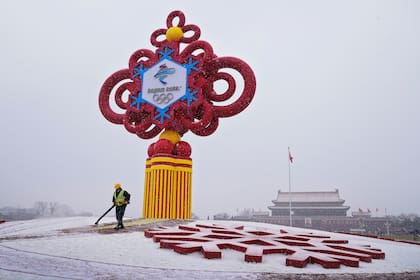 ARCHIVO - Un trabajador utiliza maquinaria para retirar la nieve de un adorno alusivo a los Juegos Olímpicos de Invierno, en la Plaza de Tiananmen en Beijing, el 20 de enero de 2022 (AP Foto/Andy Wong, archivo)