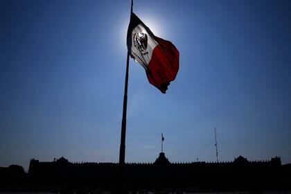 Archivo.- Una bandera mexicana ondea frente al Palacio Nacional, la oficina del presidente, en la plaza principal de la Ciudad de México, el Zócalo, al amanecer del 24 de abril de 2023. Las elecciones generales de México, incluidas las presidenciales, están programadas para el 2 de junio de 2024