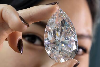 ARCHIVO - Una empleada de Christie's muestra "The Rock", un diamante blanco de 228.31 quilates _anunciado como el mayor de su tipo jamás subastado_, en una presentación previa en Christie's, el 6 de mayo del 2022, en Ginebra. (Salvatore Di Nolfi/Keystone vía AP)