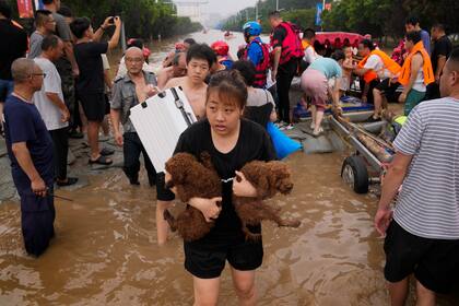 ARCHIVO - Una mujer carga a sus perros en una evacuación el miércoles 2 de agosto de 2023 debido a inundaciones en el municipio de Zhuozhou, provincia de Hebei, en el norte de China. (AP Foto/Andy Wong, archivo)