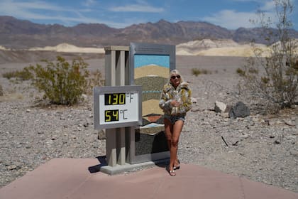 ARCHIVO - Una mujer posa junto a un termómetro el domingo 16 de julio de 2023, en el Parque Nacional del Valle de la Muerte, California. (AP Foto/John Locher, archivo)