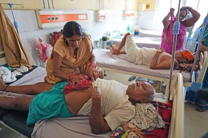 ARCHIVO - Una mujer refresca el cuerpo de su esposo con una tela fría en un hospital del gobierno en Ballia, en el estado deUttar Pradesh, India, el lunes 19 de junio de 2023. Mientras el planeta bate récords de calor, debilitando y enfermando a la gente, merece la pena recordar que las olas de calor han inspirado esfuerzos por prevenir sus efectos. (AP Foto/Rajesh Kumar Singh, Archivo)