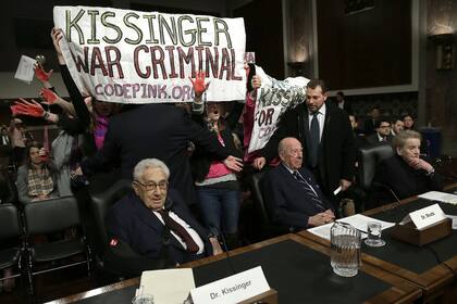 (ARCHIVOS) Los manifestantes gritan "Arresten a Henry Kissinger por crímenes de guerra" durante el Comité de Servicios Armados del Senado el 29 de enero de 2015 en Washington