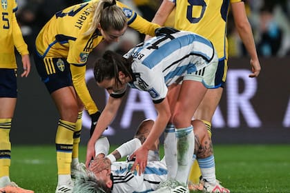 Sophia Braun consuela a Yamila Rodríguez, que yace en el césped, mientras una futbolista sueca también se acerca a brindar ánimo