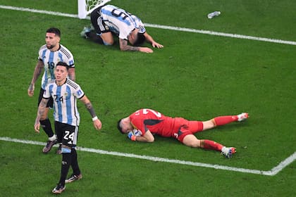 La pelota descansa en las manos de Dibu Martínez, mientras Nicolás Otamendi y Enzo Fernández, que se arrojaron sobre el arquero para festejar la espectacular atajada, se retiran de la escena