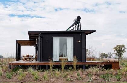 Armaron un deck a cada lado de la casa con toldos perforados que reparan el viento y dejan pasar la luz. En el frente, armaron un sector para compartir comidas durante el verano.