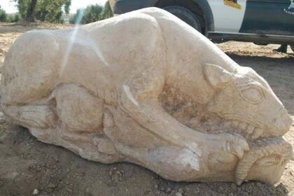 Pudo ver las fauces y las patas de una estatua que yacía semienterrada de costado bajo el suelo fértil