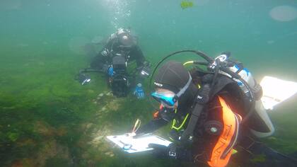 Arqueólogos dibujando los restos encontrados bajo el agua