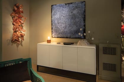 Arriba del mueble laqueado, un cuadro de Vicente Grondona, realizado en carbón, y al costado, una obra en cobre hecha por Gerardo.