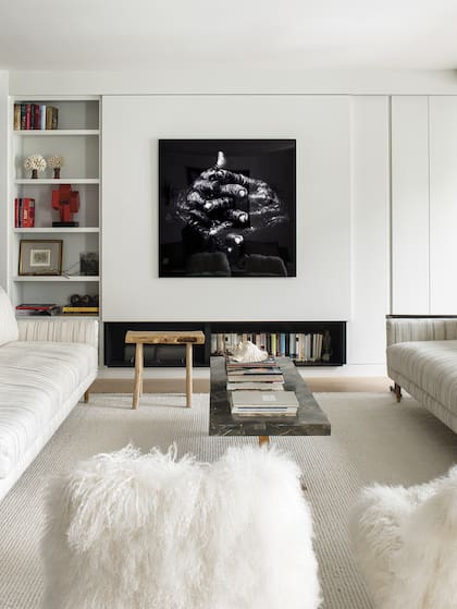 Arriba, un panel corredizo oculta TV. Abajo, la boca de la chimenea aloja libros y una estufa de bioetanol.