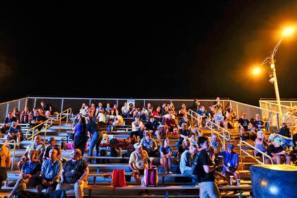 Los espectadores se sientan en una grada cerca del centro de visitantes del Saturno V varias horas antes del lanzamiento programado del cohete lunar de la NASA para la misión Artemis 1 para orbitar la Luna en el Centro Espacial Kennedy, el lunes 29 de agosto de 2022, en Cabo Cañaveral, Florida.