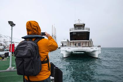 Un turista toma fotos de un barco turístico híbrido cuando se acerca al puerto de Longyearbyen
