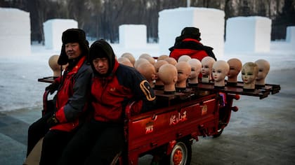 Trabajadores transportan cabezas de maniquies en el Festival Internacional de Escultura en Hielo y Nieve de Harbin