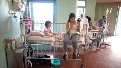 Ashley, una niña de 3 años, en el hospital Universitario de Caracas, mientras su madre, Oriana Pacheco, lee una receta